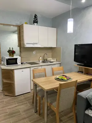 a kitchen with a table and a kitchen with white cabinets at Apartmani Dušica Konaci Kopaonik in Kopaonik