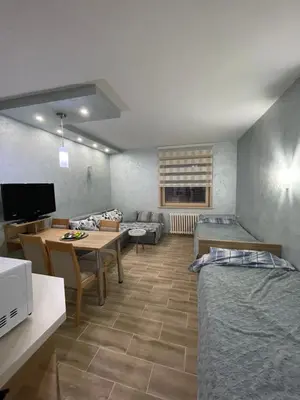 a living room with two beds and a table at Apartmani Dušica Konaci Kopaonik in Kopaonik