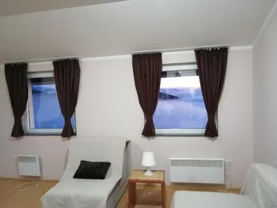 a living room with two windows and a chair at Apartman Horizont Kop in Kopaonik