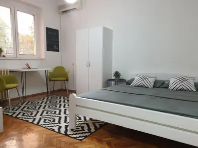 a bedroom with a bed and a table and chairs at Apartman Park Jagodina-studio u centru grada FREE parking in Jagodina