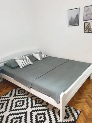 a large bed in a room with a white wall at Apartman Park Jagodina-studio u centru grada FREE parking in Jagodina