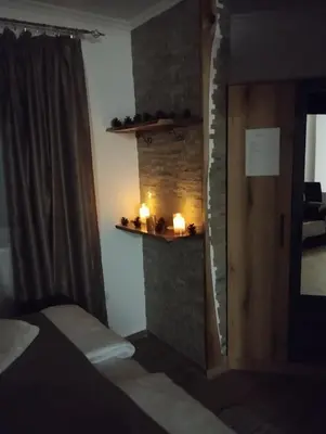 a bedroom with a bed and a stone wall with candles at Lela Kop in Kopaonik