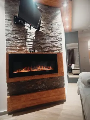 a fireplace with a tv on a stone wall at Lela Kop in Kopaonik