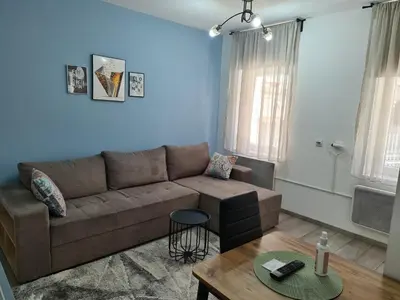 a living room with a brown couch and a table at IN Apartmani in Kruševac