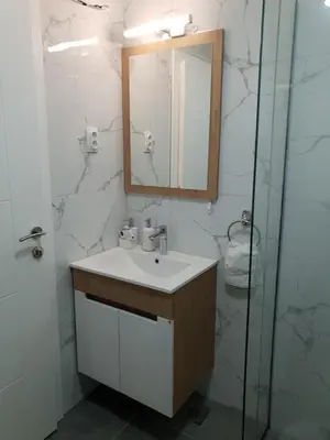 a bathroom with a sink and a mirror and a shower at IN Apartmani in Kruševac