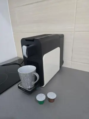 a black and white microwave sitting on a counter with a cup at IN Apartmani in Kruševac