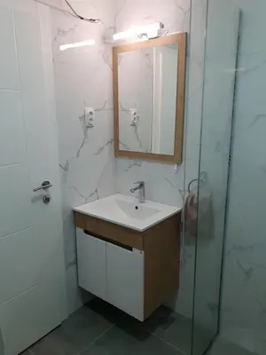 a bathroom with a sink and a mirror and a shower at IN Apartmani in Kruševac