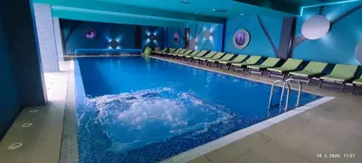 a swimming pool in a hotel with green chairs at Apartman Studio Lux u Kraljevim Čardacima in Kopaonik