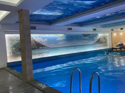 a swimming pool in a room with a painting of the ocean at Milmari Resort N73 Ski & Spa in Kopaonik