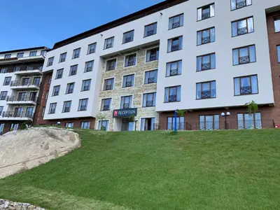 a large white building with a lawn in front of it at Milmari Resort N73 Ski & Spa in Kopaonik