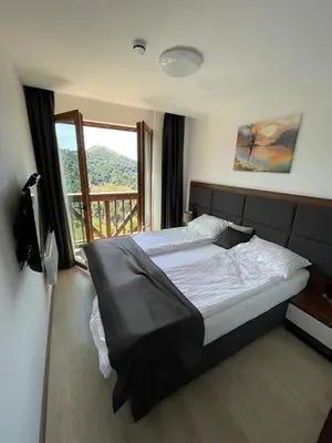 a bedroom with a large bed and a window at MK Apartments Zoned 2 Spa&Wellness in Cajetina