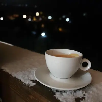 a cup of coffee sitting on a table in the snow at MK Apartments Zoned 2 Spa&Wellness in Cajetina
