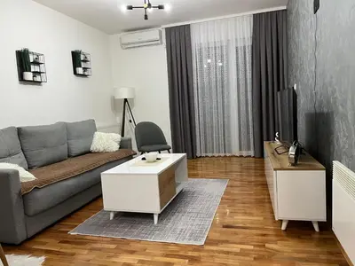 a living room with a couch and a tv at Apartman Lux in Vranje