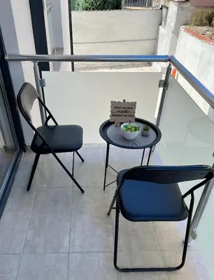 a balcony with two chairs and a table and a bowl of food at Apartman Lux in Vranje