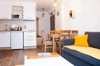 a kitchen and a living room with a couch and a table at Apartman Paunovi Čardaci sa garažnim mestom in Kopaonik