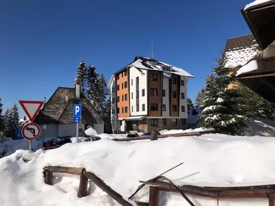 a building with a pile of snow in front of it at Vila Montana Kopaonik Apartman 6 in Kopaonik