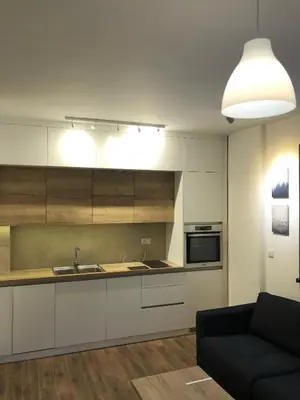 a kitchen with white cabinets and a black couch at Vila Montana Kopaonik Apartman 6 in Kopaonik
