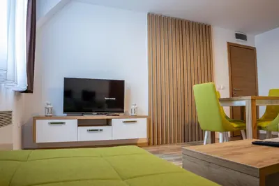 a living room with a television and a table and chairs at SUNČANI BREG RESORT & SPA apartment 14 Kopaonik in Kopaonik
