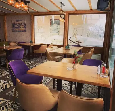 a restaurant with wooden tables and purple chairs at SUNČANI BREG RESORT & SPA apartment 14 Kopaonik in Kopaonik