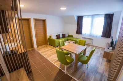 a dining room with a table and green chairs at SUNČANI BREG RESORT & SPA apartment 14 Kopaonik in Kopaonik