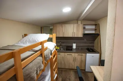 a small room with two bunk beds and a kitchen at Apartmani SP Jovanovic in Crni Vrh