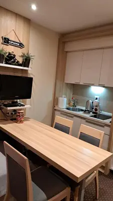 a kitchen with a wooden table with chairs and a television at GALA Kop Apartman in Kopaonik