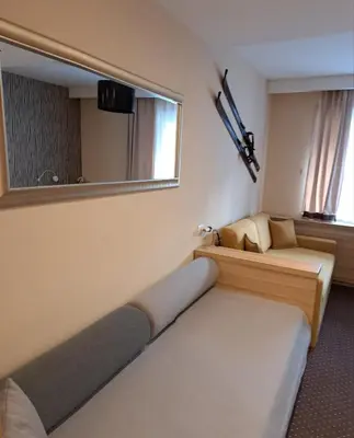 a small room with two beds and a mirror at GALA Kop Apartman in Kopaonik