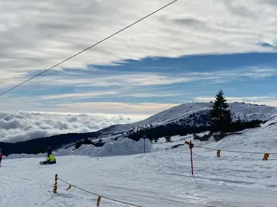a person riding a snowboard down a snow covered slope at GALA Kop Apartman in Kopaonik