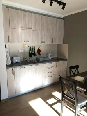 a kitchen with wooden cabinets and a table with a chair at Apartman 217 in Kopaonik