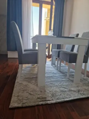 a white dining table and chairs on a rug at Apartman In Lux in Vrnjačka Banja