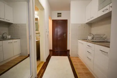 a kitchen with white cabinets and a brown door at Apartman In Lux in Vrnjačka Banja