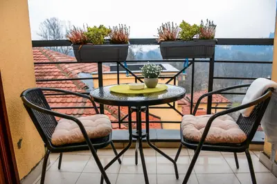 a table and chairs on a balcony with plants at Apartman In Lux in Vrnjačka Banja