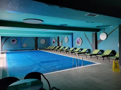 a large swimming pool with chairs in a building at JORDAN Apartment KC 9C 35 Kopaonik in Kopaonik