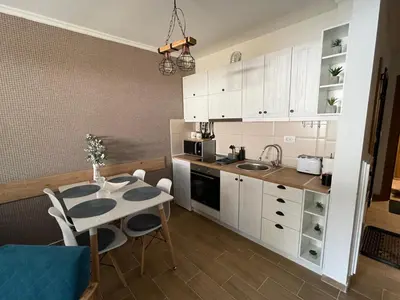 a kitchen with white cabinets and a table and chairs at Vili.Kop studio in Kopaonik