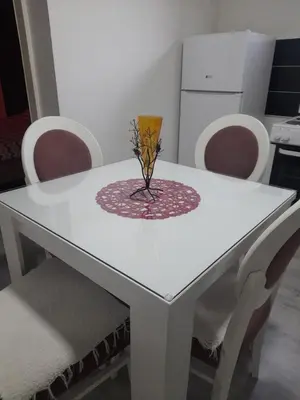 a white table with chairs and a vase on it at Family Apartmani Le in Leskovac