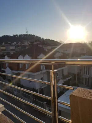 a view of a city from a balcony with the sun at Family Apartmani Le in Leskovac