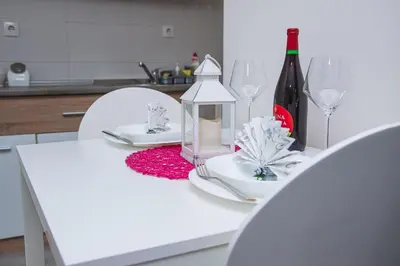 a white table with a bottle of wine and glasses at Family Apartmani Le in Leskovac