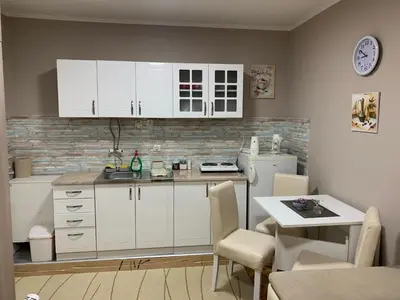 a kitchen with white cabinets and a table and a counter at Apartman Djuric Paracin in Paraćin