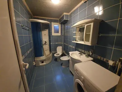 a blue tiled bathroom with two toilets and a sink at Smestaj Boki in Soko Banja