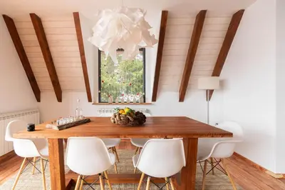 a dining room with a wooden table and white chairs at Vista Mountain House in Kopaonik