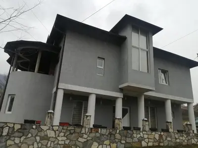 a gray house with a stone retaining wall at ORTODOKS in Brus
