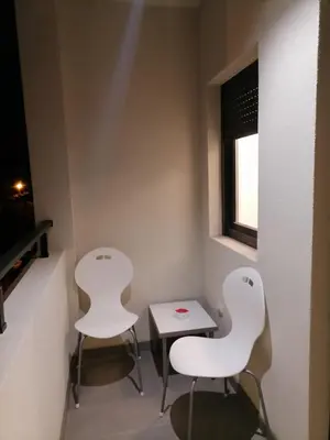 two white chairs and a table in a room at APARTMAN ANA in Niš
