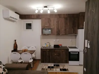 a kitchen with wooden cabinets and white appliances at APARTMAN ANA in Niš
