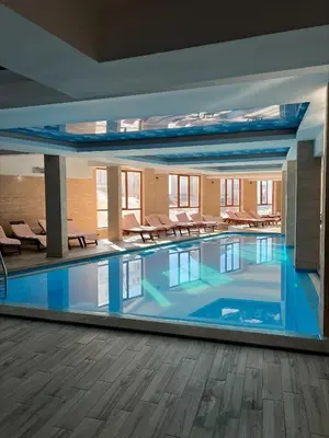 a large swimming pool in a building with chairs at Milmari Apartman Haski N55 in Kopaonik