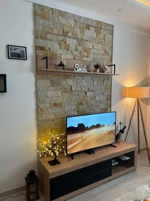 a living room with a flat screen tv on a stone fireplace at Milmari Apartman Haski N55 in Kopaonik