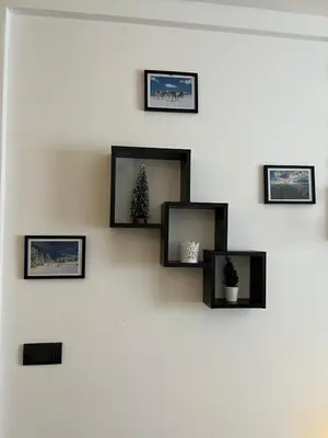 a wall with four framed pictures and a christmas tree at Milmari Apartman Haski N55 in Kopaonik