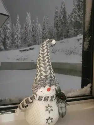 a snowman doll with a hat sitting in a window at Kai Apartman in Kopaonik