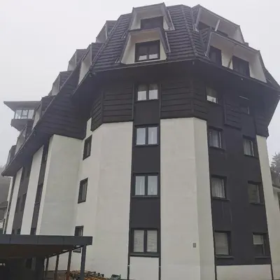 a tall black and white building with a roof at Kai Apartman in Kopaonik