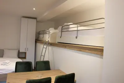 a room with a table and two bunk beds at Apartmani Sorak Kopaonik, Studio Apartman A10 in Kopaonik