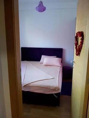a small bed with white sheets and pink pillows at Apartman Mihajlovic in Soko Banja